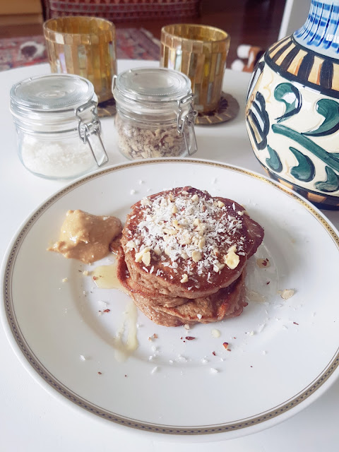 healthy banana pancakes topped with peanutbutter, hazelnuts and shredded coconut