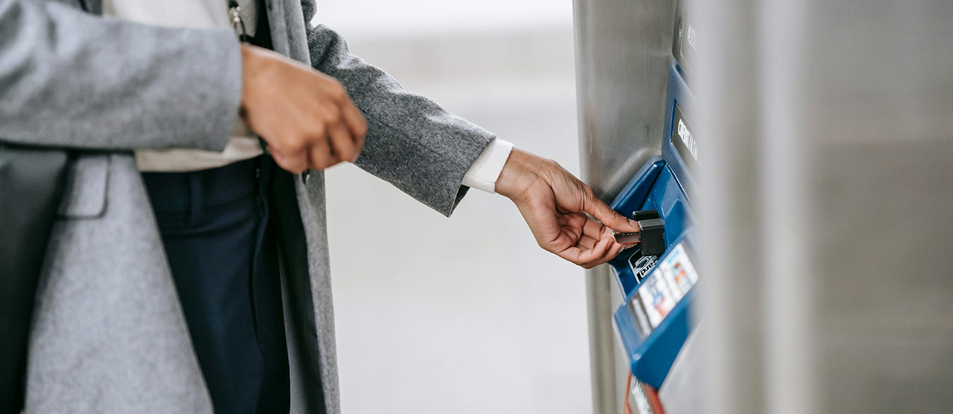 Close-up, side view photo of a person putting in their debit/credit card into an ATM machine whilst abroad.