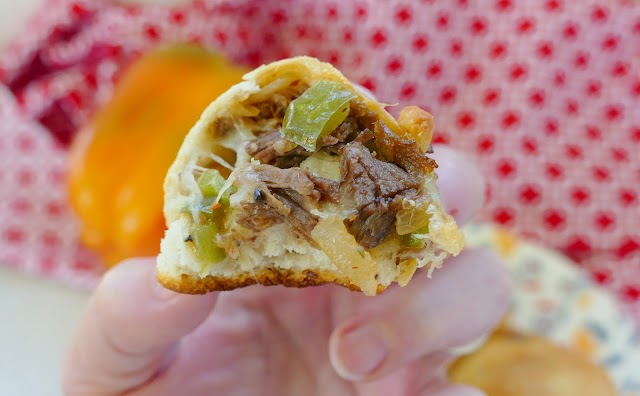 Cheesesteak Biscuit Bite held by a hand with a bite out of it.