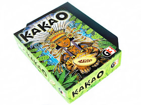 na zdjęciu pudełko gry kakao, okładka przedstawia piękna indiankę z kolorowym, kwiecistym pióropuszem na głowie, ziarnem kakaowca w rękach, otoczoną przez roślinność 