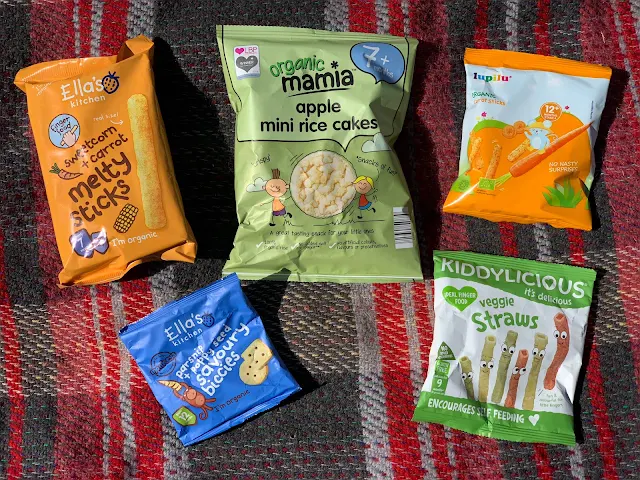 A selection of bags of baby snacks from the supermarket including Ella's Kitchen, Aldi Mamia, Kiddylicious and Lidi Lupilu