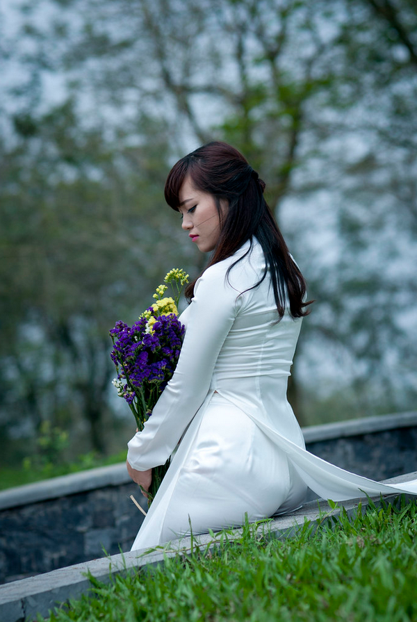 Thiếu nữ ngồi áo dài trắng ôm hoa