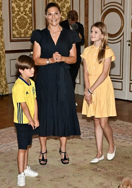 Crown Princess Victoria wore a black v-neck dress by Malina. Princess Estelle wore a yellow shirt dress by Dagmar