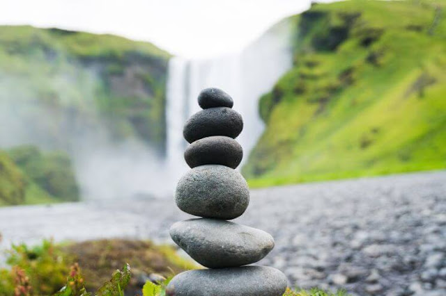 stack of river stones balanced in front of a waterfall