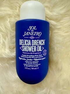 Sol de Janeiro Delícia Drench Shower Oil bottle placed on a soft white fluffy background, showcasing vibrant packaging