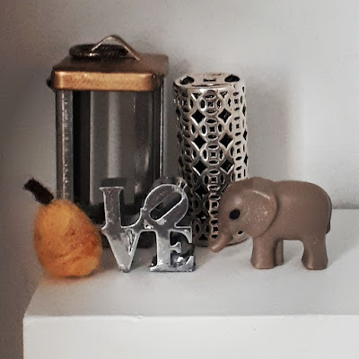 One-twelfth scale modern miniature collection of decor items including a candle lantern, vase, felted pear, love sculpture and elephant.