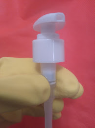 The pump from a bottle of hand soap being grasped between thumb and forefinger just below the lid