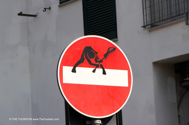 A sticker of a guitar player smashing his guitar on the ground stuck on a regular No entry-street sign.