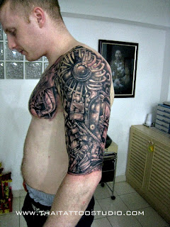 biomechanic tattoo with mechanical elements and alien tissues covering the shoulder, the chest and the arm