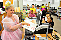 Students getting the royal service checking out books from Queen Jeanne at the Wright Elementary Library.