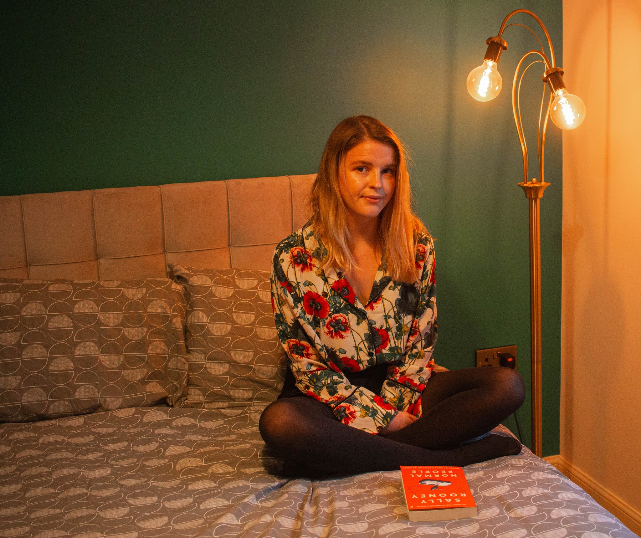 blonde girl chloe harriets sat on bed reading normal people by sally rooney for chloe harriets 2020 book club