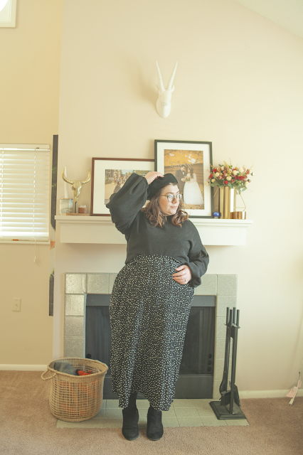 An outfit consisting of a black wool beret, black balloon sleeve tucked into a black and white micro dot maxi skirt and black ankle boots.
