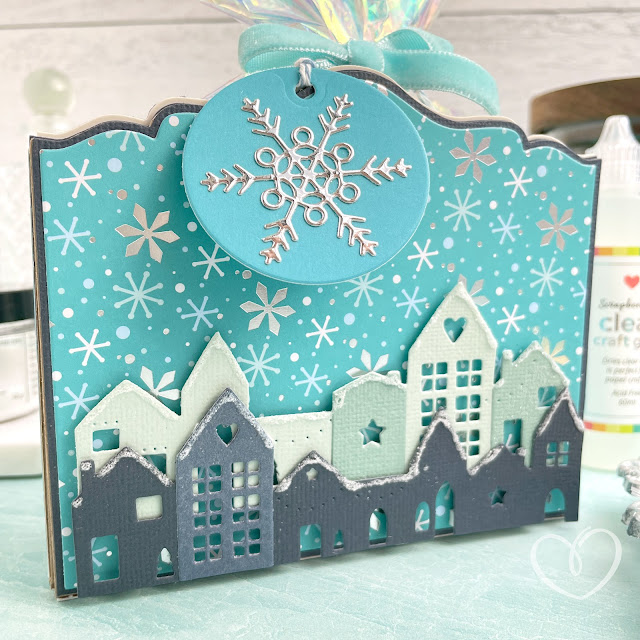 Treat box made with the Sizzix Card Caddy die, Starlit Village die, Everyday Tags and Labels die, Cardstock Surfacez, and patterned paper; as well as Scrapbook.com adhesives and Tim Holtz Distress Rock Candy Glitter.