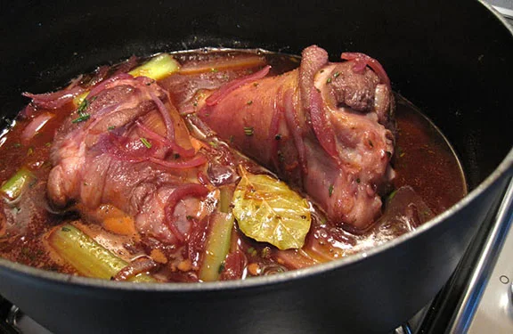 Lamb shanks in a cast iron casserole ready to cook in the oven.