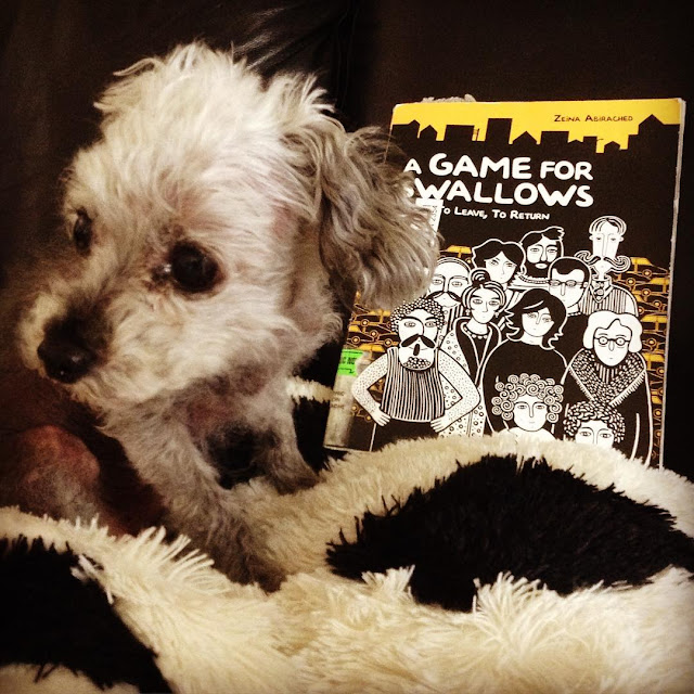 Murchie hunches down and looks away from a trade paperback copy of A Game For Swallows. The book's cover features a black and white illustration of many adults of multiple genders gathered behind two small, curly-haired children. Everyone looks very serious.