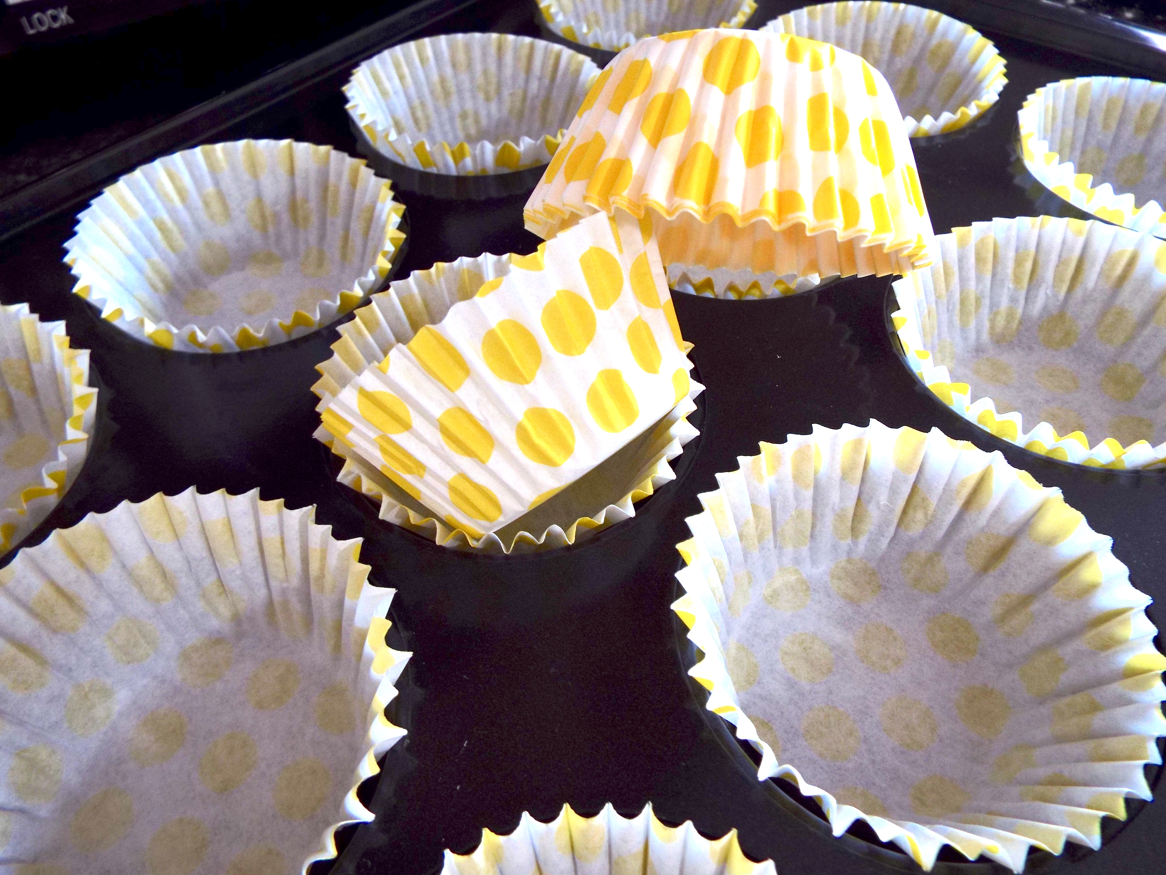 Yellow polka dotted cupcake cases ready in baking tray.
