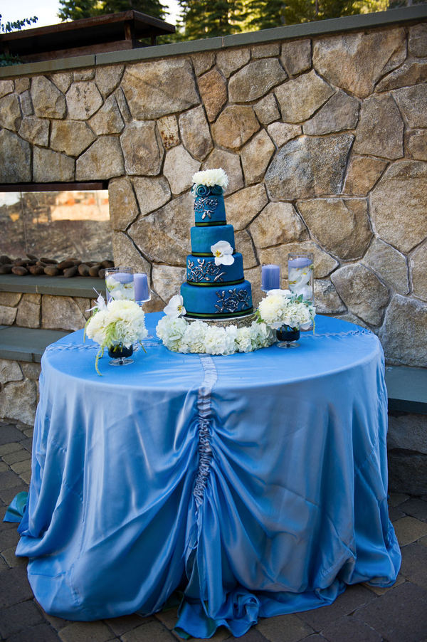 A beautiful rich blue wedding cake set over four tiers adorned with fresh 