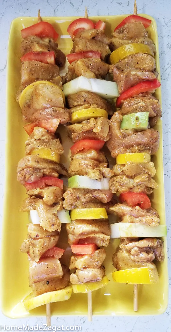 Plate of raw chicken and vegetable kebabs