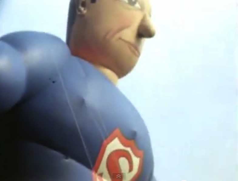 Close-up of inflated Superman balloon, with cartoonish face and vintage 'S' insignia