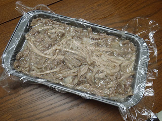 The pulled meat packed into a loaf pan lined with plastic wrap