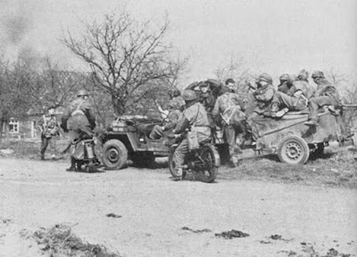 Wartime photo shows motorcycles and Jeep with airborne soldiers.