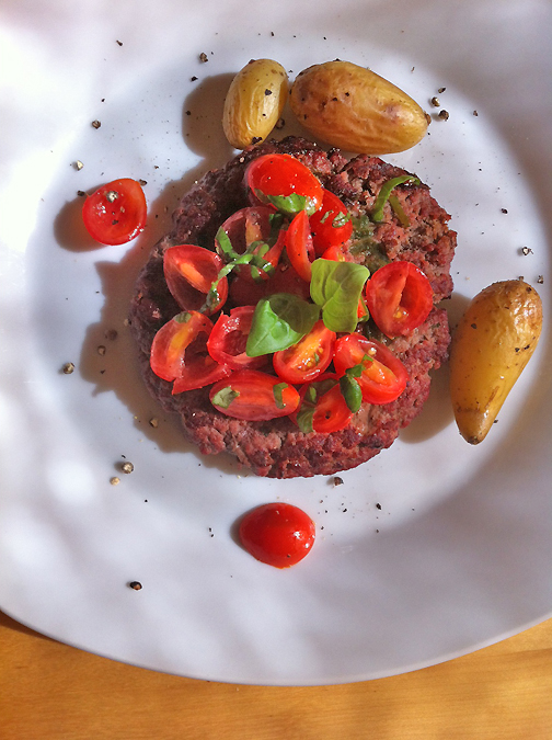 Bikini Burger with grape tomato salad with fresh basil, side of fingerling potatoes on white plate