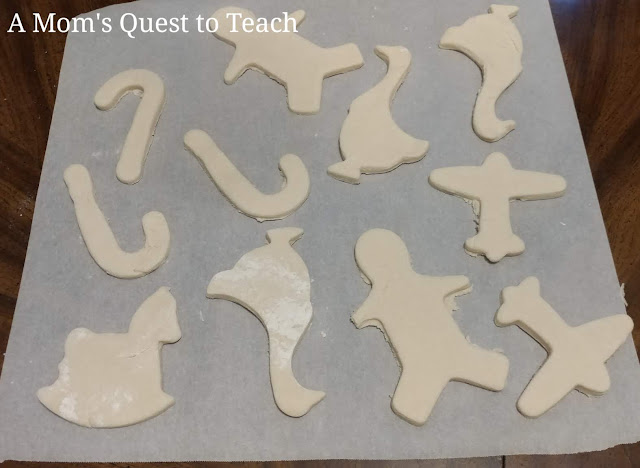 collection of salt dough ornaments on parchment paper - candy cane, rocking horse, goose, air plane, gingerbread man