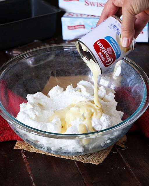 Pouring Sweetened Condensed Milk into a Bowl of Whipped Cream Image