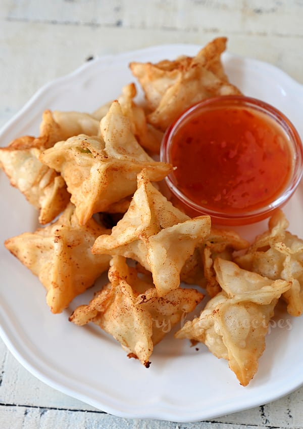 top view of a white plate with crab rangoon served with sweet chili sauce