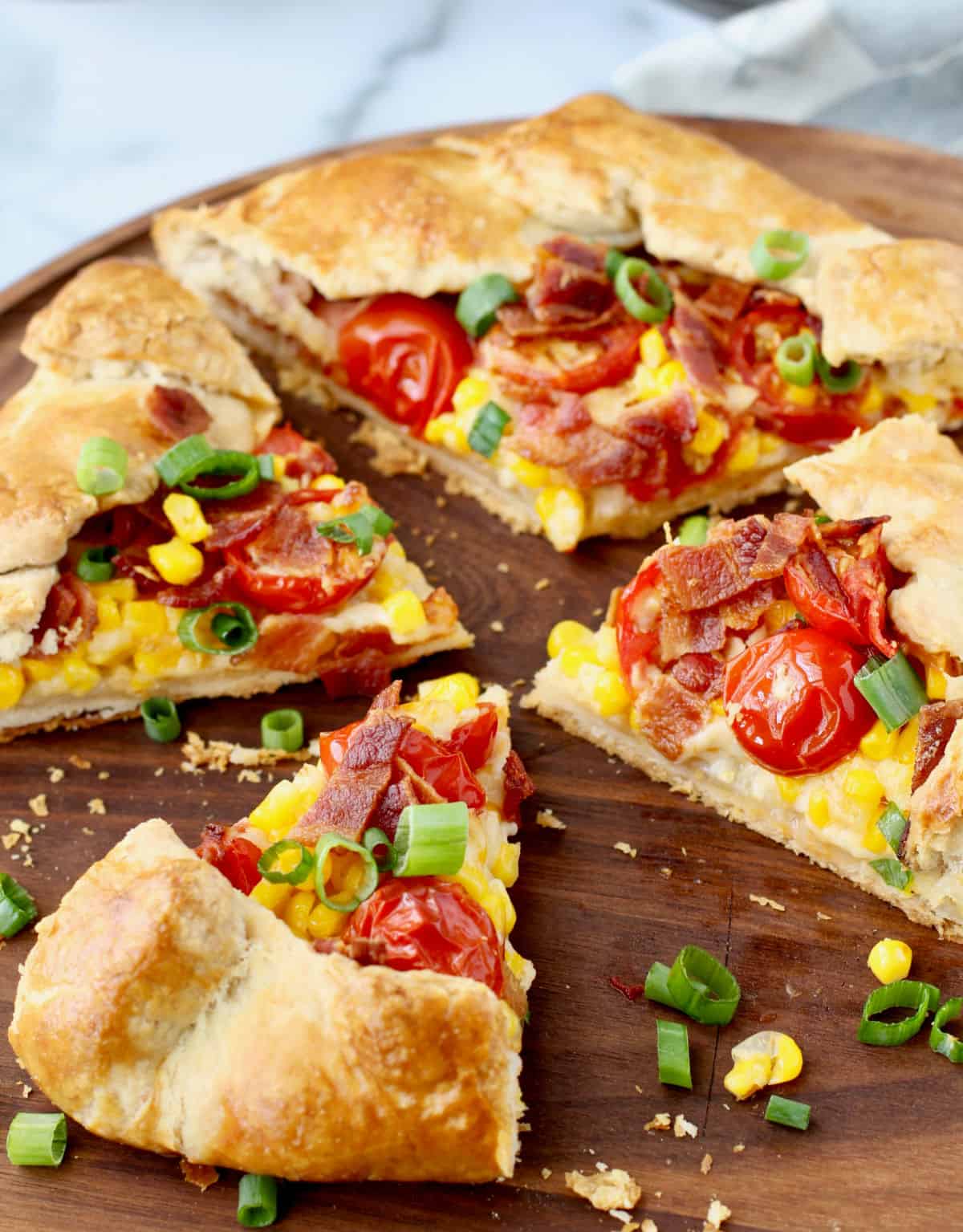 Bacon, Tomato, and Corn Galette with flaky crust crumbs on the cutting board.