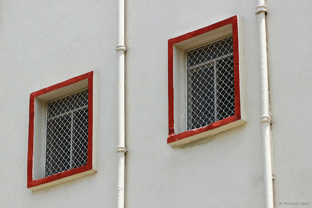 A Minimal Art Photograph of Two Windows with Red Borders on a White Wall shot by Canon 100 mm prime Macro lens on a Crop Sensor Canon 600D Camera. Picture taken at Ravindra Manch, Jaipur, (Rajasthan)  during Jaipur Art Summit.