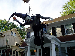 A giant witch being lifted onto a roof by a crane