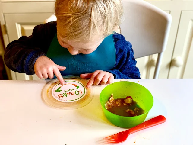 Little looking at the lid of a Logan's Plate meal