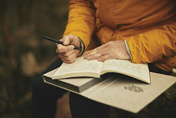 A person in a yellow jumper writing down their thoughts as part of a healthy habit in a book or journal
