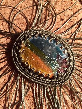 Pierced leather cabochon with attached macrame.