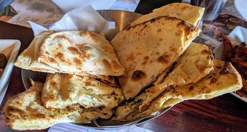 A bowl with quartered regular and garlic naan