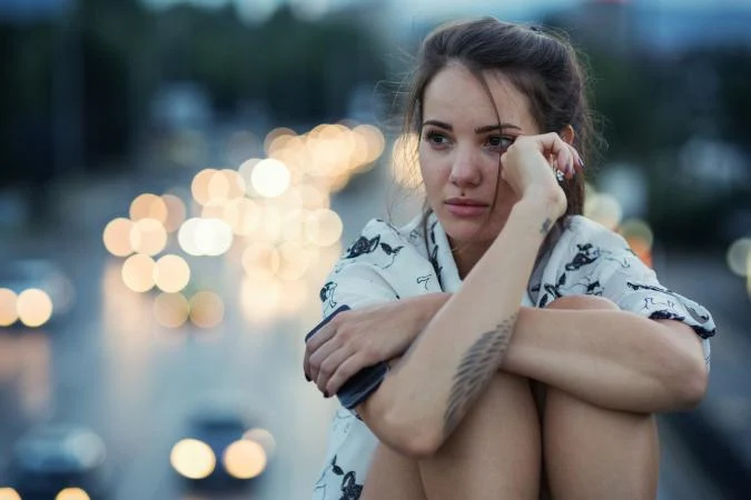 Imagen de joven modelo con tatuaje en brazo melancólica de fondo la ciudad