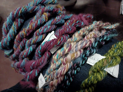 eight tiny skeins of sample yarn, mostly blue and pink with other colors mixed in.
