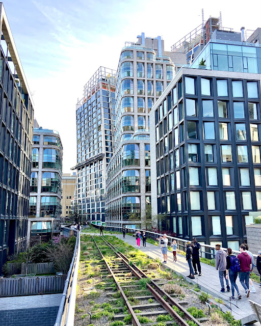 Tourists walk on the High Line in New York as luxury condos line the sides of the park.