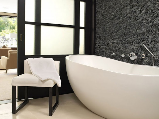Black bathroom in the Aspen Residence by Stonefox with white bath tub and a single black chair