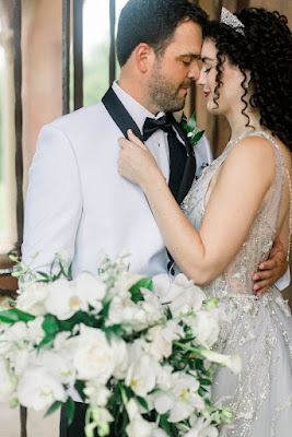 bride holding grooms tux with white and green bouquet