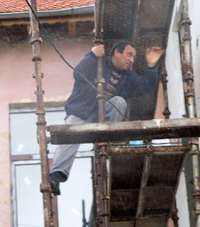 Bekir up a scaffold in the rain