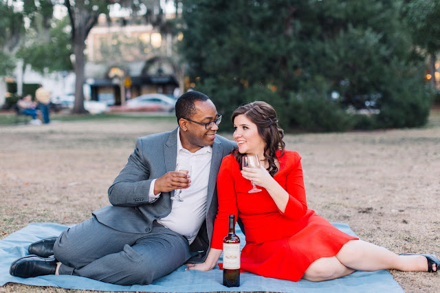 engaged couple drinking wine picnic in the park