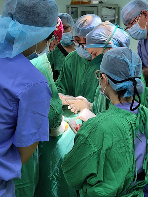 IEP medical team performing a surgical procedure on a patient's lower leg in Can Tho, Vietnam.