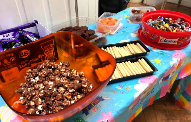 image shows a table covered with food - cakes, chocolate and sweets