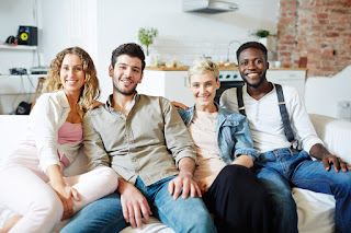 A bunch of tall women and men with different hair styles wearing white shirts and black pants on a bright background 