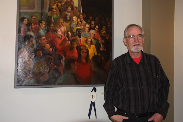 Me standing next to Let the People Out, an oil painting of people emerging from a trolley car, with First prize ribbon.
