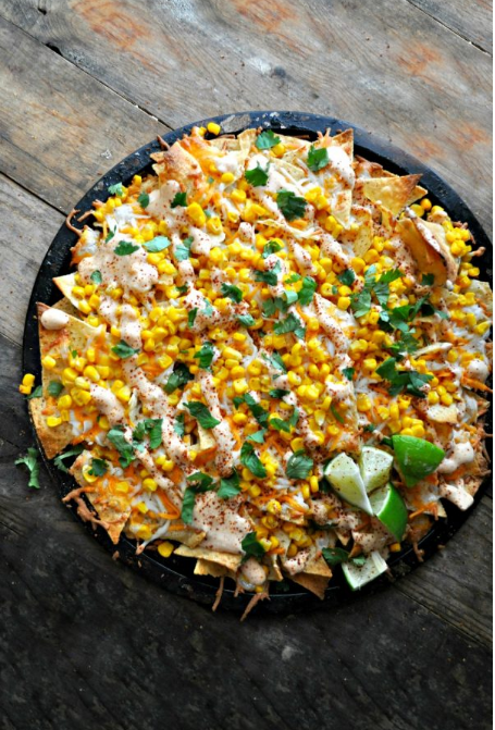 Vegan Street Corn Nachos - Layers of chips, vegan cheese and corn. Drizzled with chili lime mayo and topped with cilantro.