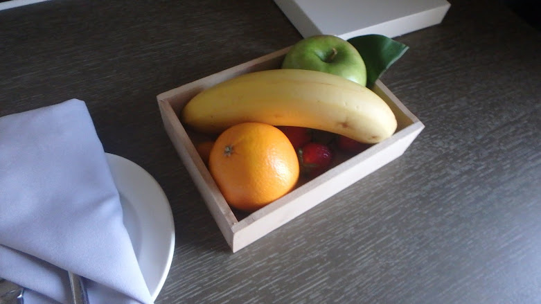 A small square wooden box containing an apple, a banana, and an orange.
