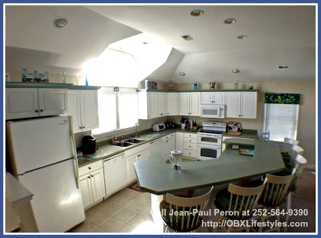 The large kitchen of this Outer Banks NC home for sale in Ocean Sands comes with a refrigerator with ice maker, a dishwasher, a microwave oven, and a 5 burner glass top stove top and double oven.